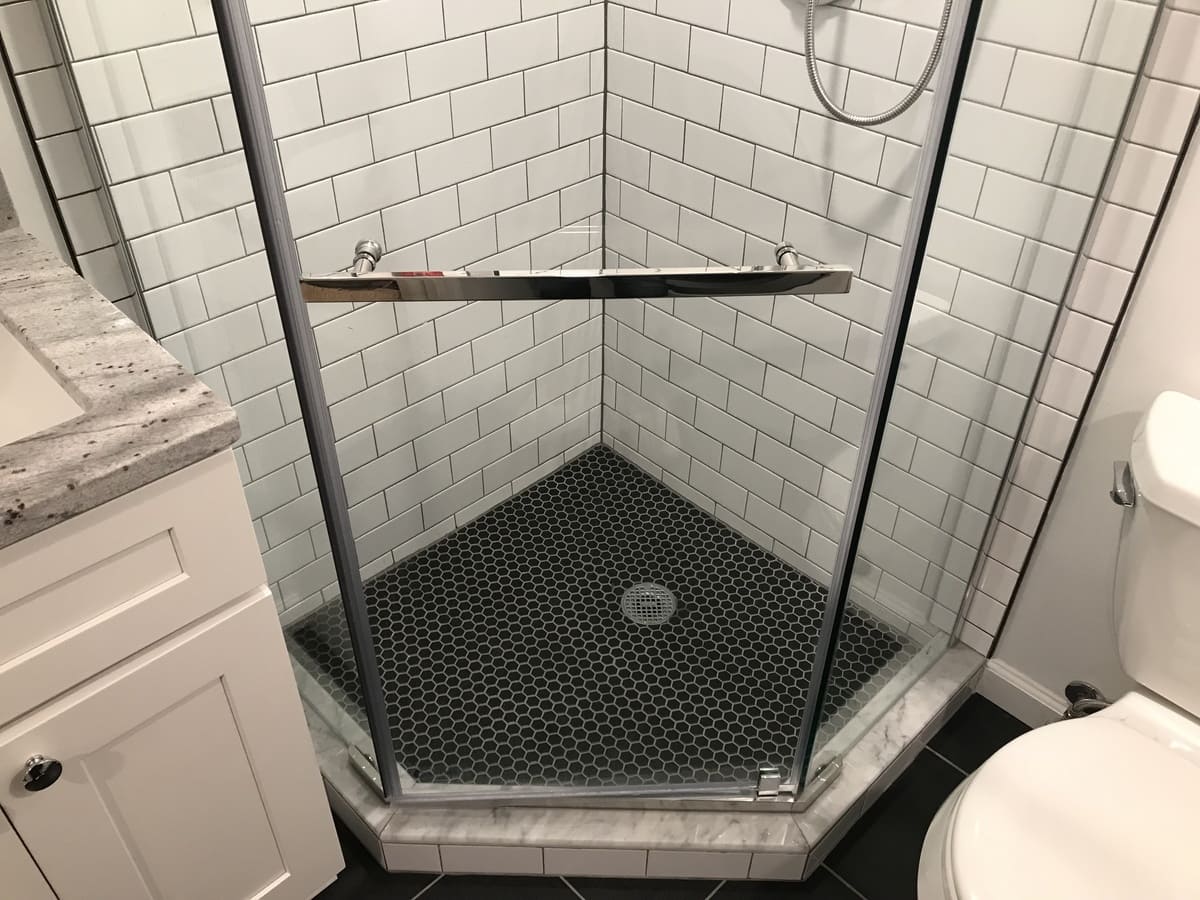 Shower remodel with white subway tile and black tile flooring